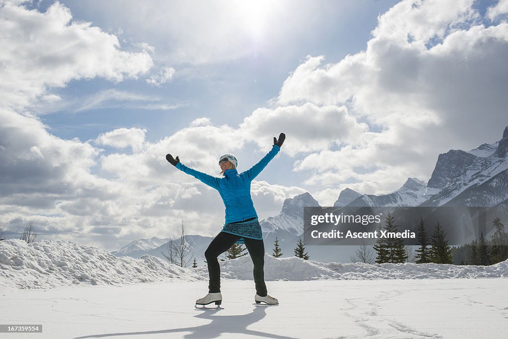 Woman skates on frozen pond under snowy mountains