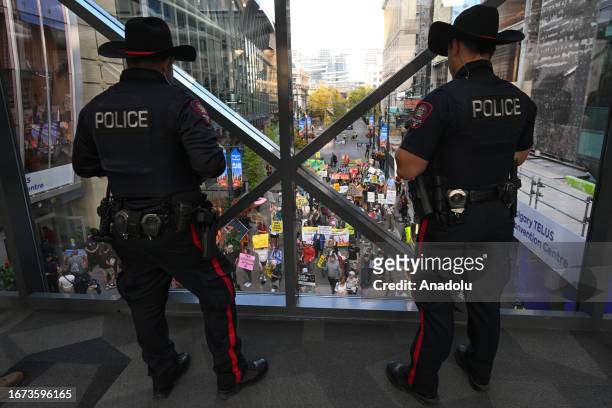 Activists are watched by police officers during a 'Rally for Climate Sanity' outside Calgary's Town Hall in opposition to the 24th World Petroleum...