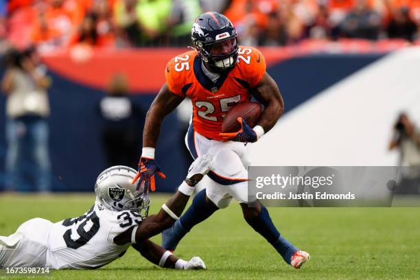 Running back Samaje Perine of the Denver Broncos runs with the football against cornerback Nate Hobbs of the Las Vegas Raiders Raiders during the...