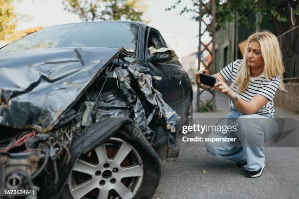 mid adult woman taking photo of wrecked car - wreck stock pictures, royalty-free photos & images