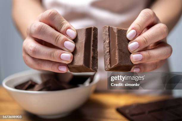 human hands breaking chocolate - dark chocolate stock pictures, royalty-free photos & images