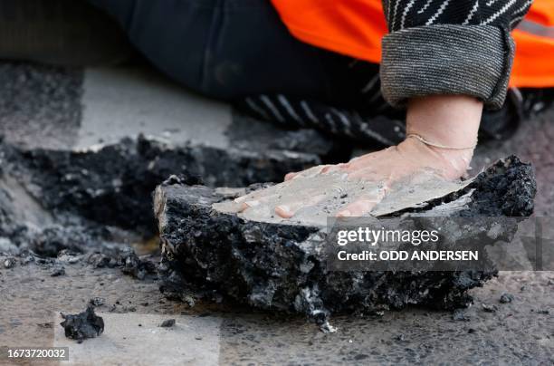 Climate activist who glued herself to the street in order to draw attention to the climate emergency has a piece of road surface on her hand as...