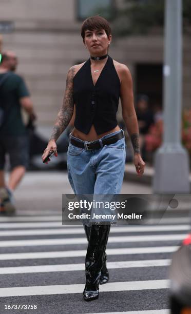 Guest is seen outside Khaite show wearing silver earrings, logo choker sayinng "die", denim shorts with black leather belt and silver hardware, black...