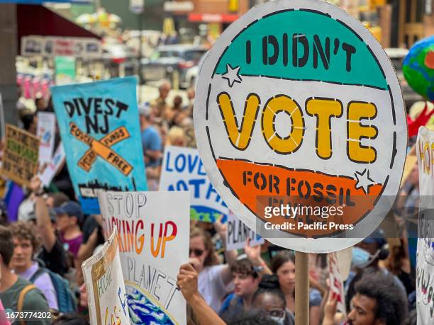 Protesters hold placards against fossil fuel expansion. Thousands of demonstrators flooded Manhattan streets demanding president Biden to take action...
