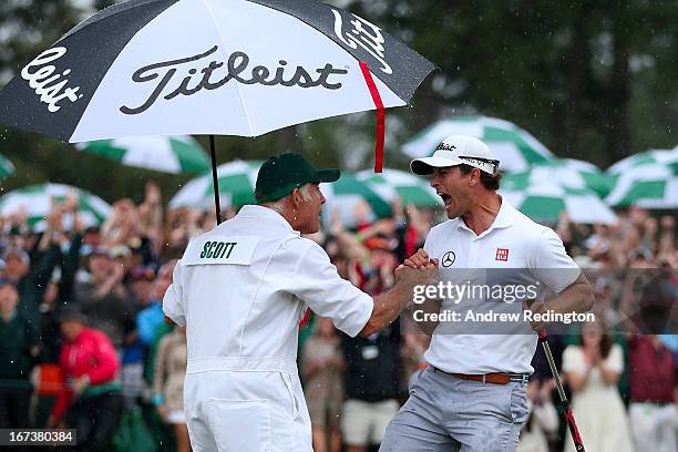 Adam Scott of Australia celebrates with caddie Steve Williams after making a birdie on the 18th hole during the final round of the 2013 Masters...