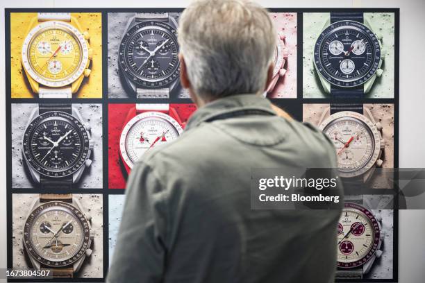 Nick Hayek, chief executive officer of Swatch Group AG, looks at a poster showing the range of Swatch x Omega MoonSwatch watches at the Swatch ETA...