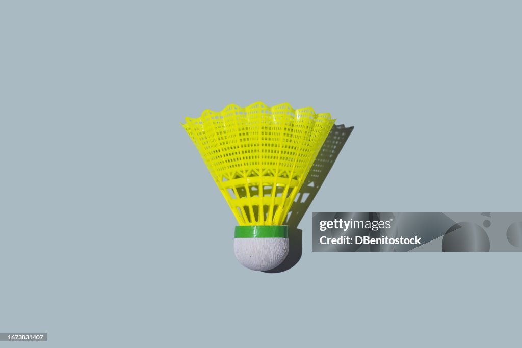 Yellow plastic badminton shuttlecock on grayish blue background. Concept of ball, shuttlecock, pen, badminton, conception, tournament and training.