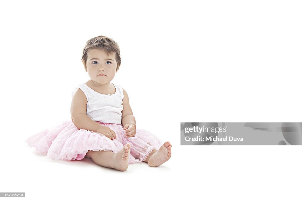 Baby calmly sitting in a tutu on white background