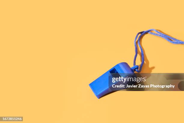 blue plastic whistle on a yellow background - spelregels stockfoto's en -beelden