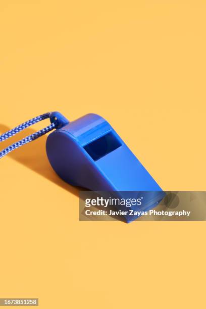 blue plastic whistle on a yellow background - punktrichter stock-fotos und bilder