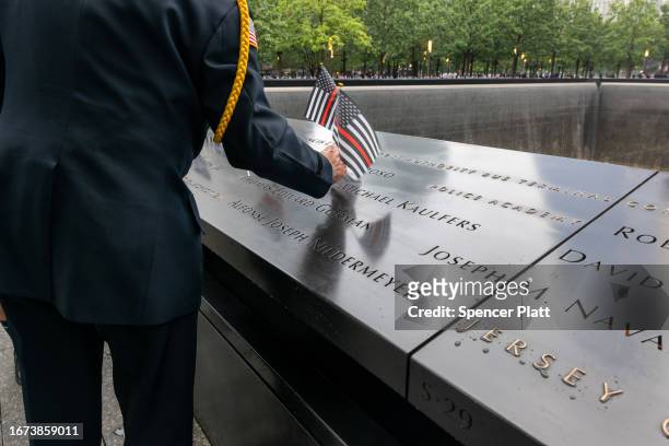 Retired police officer Sam Pulia places flags on the names along the 9/11 Memorial at the Ground Zero site in lower Manhattan as the nation...