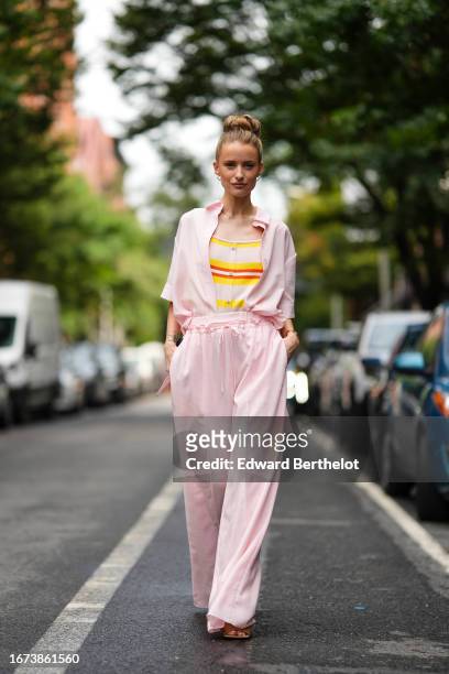 Victoria Magrath wears a pastel / pale pink shirt, a yellow and red striped top, pastel / pale pink flare / palazzo pants, outside Adeam, during New...