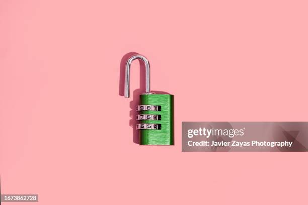 green padlock with numerical combination on pink background - unlocking stock pictures, royalty-free photos & images