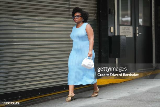 Guest wears sunglasses, a blue sleeveless long dress with stripes, a white bag, khaki shoes, outside Jason Wu, during New York Fashion Week, on...