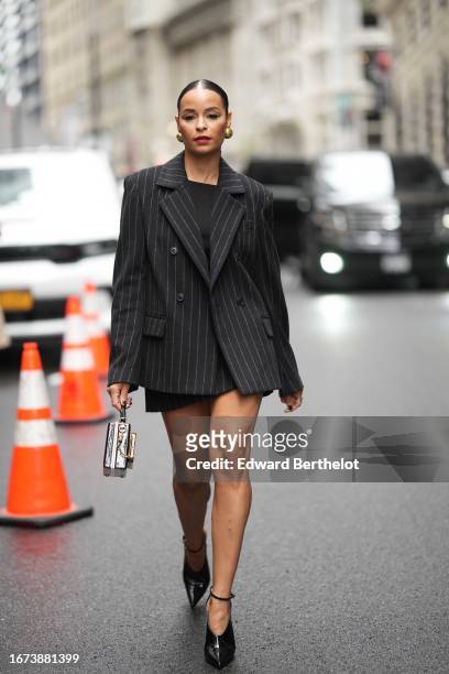 Sai de Silva wears a black oversized striped blazer jacket, a mini skirt, a bag, pointed shoes, outside Jason Wu, during New York Fashion Week, on...