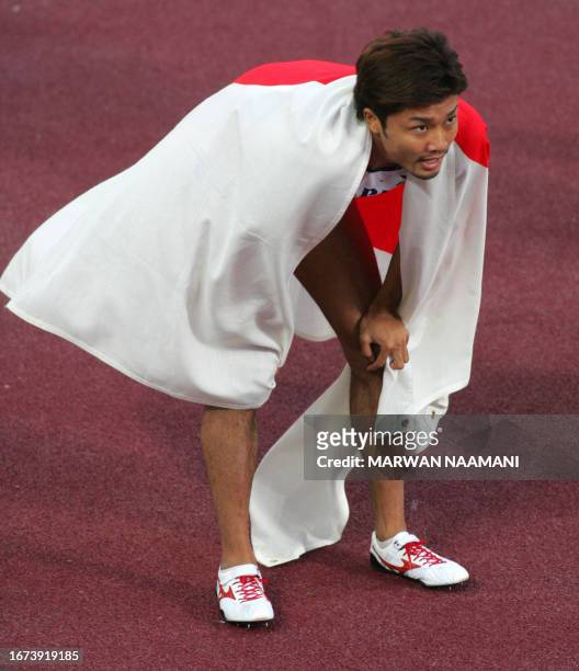 Wrapped in his country's flag, Japan's Shingo Suetsugu celebrates his victory in the men's 200m final on the fourth day of the athletics competition...
