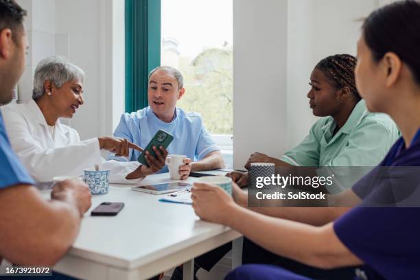 sharing stories at break time - holding up phone signal stock pictures, royalty-free photos & images