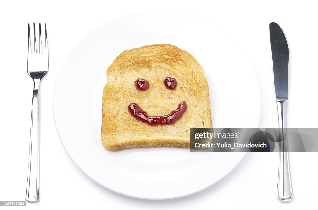 Toast with a smile of jam, fork and knife isolated