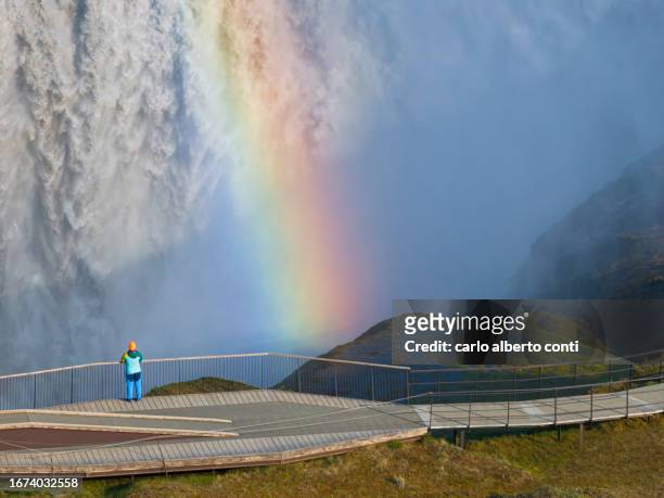a girl enjoys the beautiful view of the majestic dettifoss waterfall, iceland, europe - dettifoss waterfall stock pictures, royalty-free photos & images