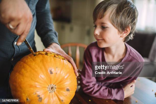 father and his little boy carving pumpkins for halloween - carve out stock pictures, royalty-free photos & images