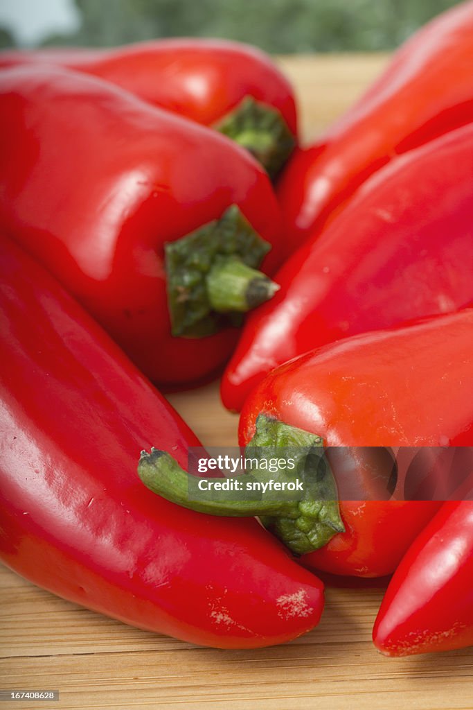 Red hot peppers on wooden cutting board.