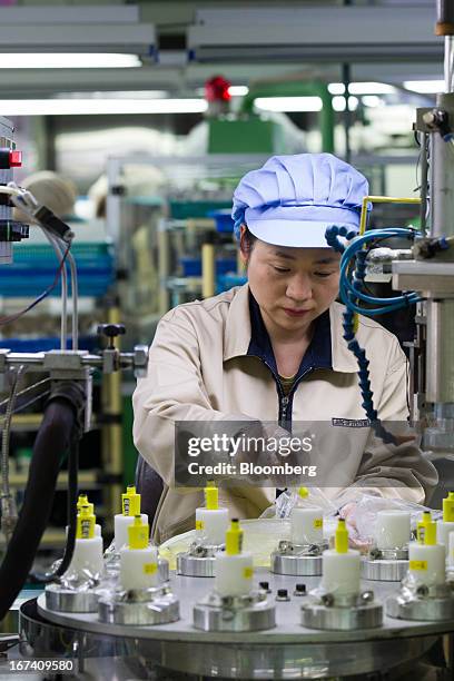 Jangup System Co. Employee puts mascara containers into an assembly machine on the production line for manufacturing cosmetic containers at the...