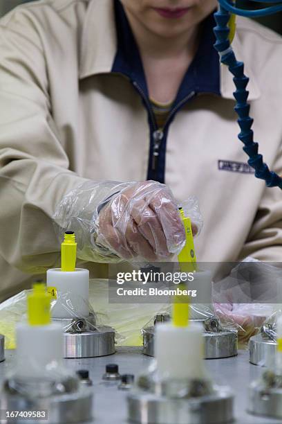 Jangup System Co. Employee puts mascara containers into an assembly machine on the production line for manufacturing cosmetic containers at the...