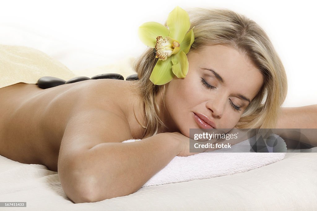 Frau entspannend mit Blumen und warmen Steinen