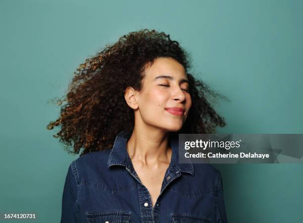 happy woman with curly hair posing in studio - zen-like stock pictures, royalty-free photos & images