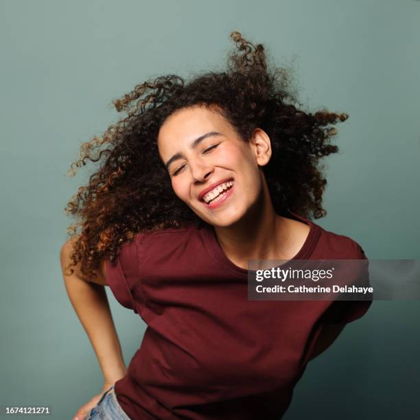 happy woman with curly hair posing in studio - visage danseuse photos et images de collection