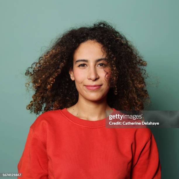 happy woman with curly hair posing in studio - facing photos et images de collection