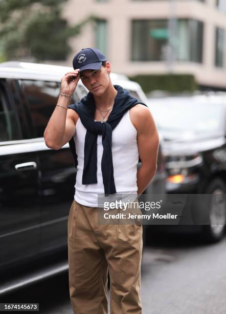 Tommy Hilfiger Fashion Brunch guest Noah Beck was seen wearing black leather shoes with little heels, brown long trousers, a white muscle shirt,...