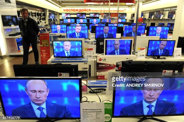 Customer walks past the TV screens in a shop in Moscow, on April 25 during the broadcast of President Vladimir Putin's televised question and answer...