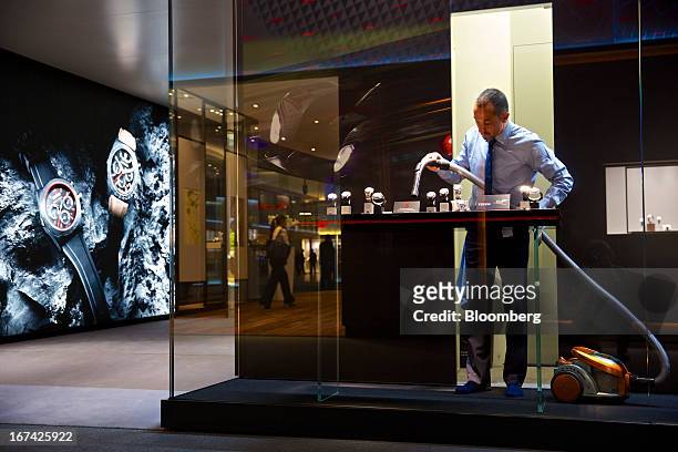 Employee vacuums a display of wristwatches at the Tudor booth during the Baselworld watch fair in Basel, Switzerland, on Thursday, April 25, 2013....