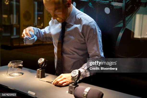 An employee cleans a display of wristwatches at the Tudor booth during the Baselworld watch fair in Basel, Switzerland, on Thursday, April 25, 2013....