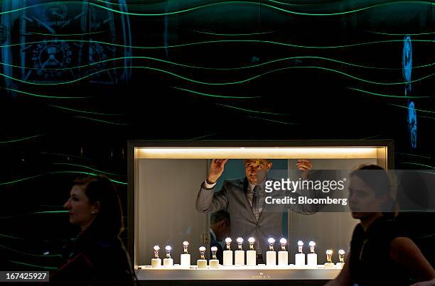 An employee opens the shutter to a display of wristwatches inside the Rolex Group booth during the Baselworld watch fair in Basel, Switzerland, on...