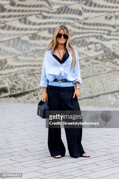 Gitta Banko, wearing a black bra-top by Johanna Ortiz, a blue oversize blouse by Boscana, dark blue pants with Jenas waistband by Dion Lee, sandals...
