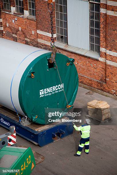 An employee secures a crane's lifting gear to a windtower section in the yard at the Enercon Windtower Production AB plant in Malmoe, Sweden, on...