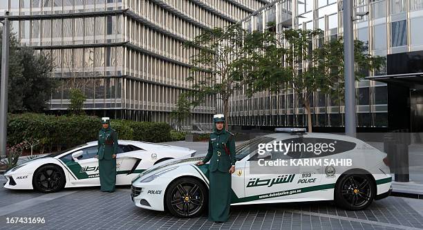Emirati female police officers pose in front of Ferrari and Lamborghini police vehicles at the foot of the Burj Khalifa tower in the Gulf emirate of...