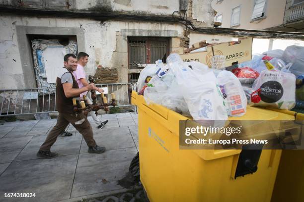 Two men walk next to an overflowing garbage container during the fourth week of the strike in Vilalba garbage collection on September 11 in Vilalba,...