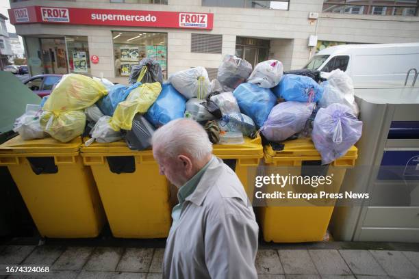 Man walks past overflowing garbage containers during the fourth week of the Vilalba garbage collection strike on September 11 in Vilalba, Lugo,...