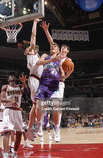 Andrei Kirilenko of the Utah Jazz is defended by Chris Andersen and Nikoloz Tskitishivili of the Denver Nuggets during the game at Pepsi Center on...