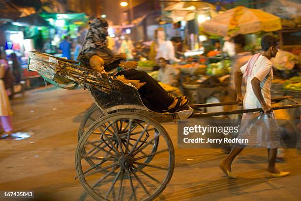 Muslim woman and son ride in a rickshaw through the night time chaos of New Market in Calcutta..