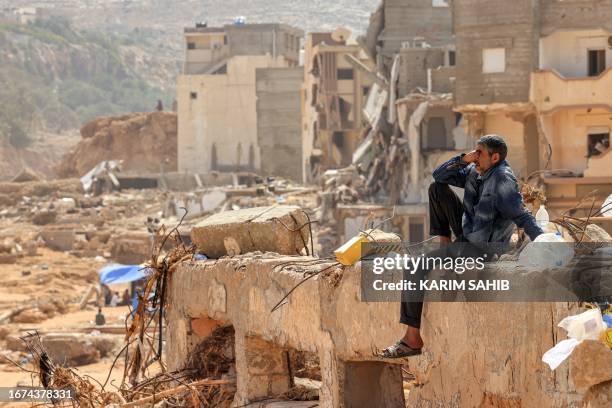 Man reacts as he sits on the rubble of a destroyed building in Libya's eastern city of Derna on September 18, 2023 following deadly flash floods. A...