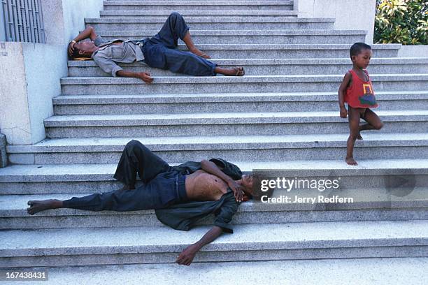 Homeless men sleep on the cool stone steps of Wat Ounalom during the heat of the afternoon..