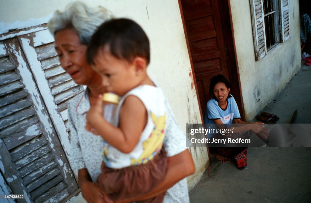 Heng Phaly, 65, holds her two-year-old grandson David as her...