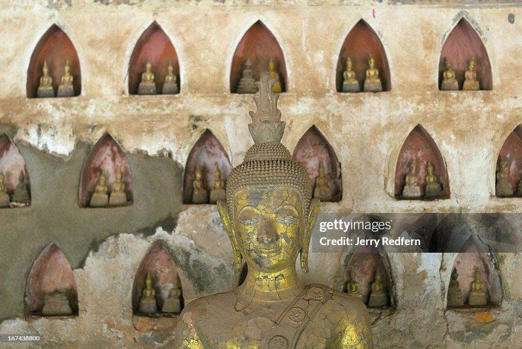 One of hundreds of Buddha statues in an alcove in Wat...
