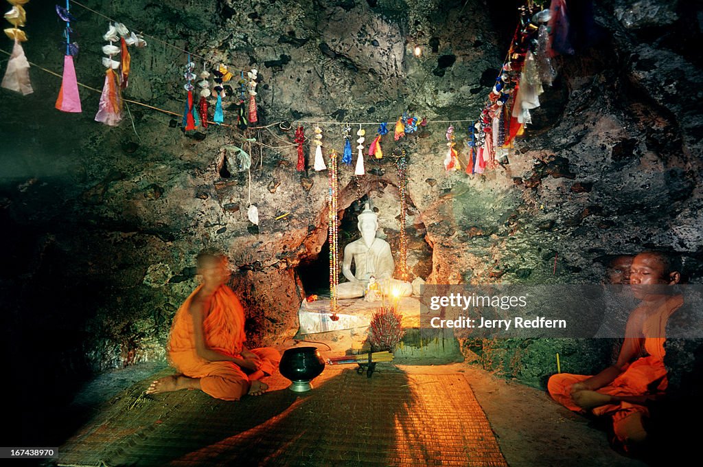 Buddhist monks pray in a cave atop Phnom Sampeau, a Buddhist...