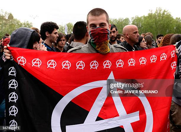 Masked demonstrator display an Anarchy flag close to the blocked street leading to the Spain's parliament during an anti-government demonstration in...