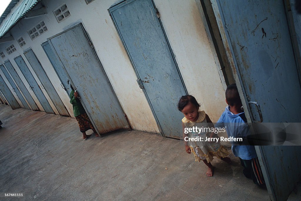 Children play around broken and abandoned shower stalls near...